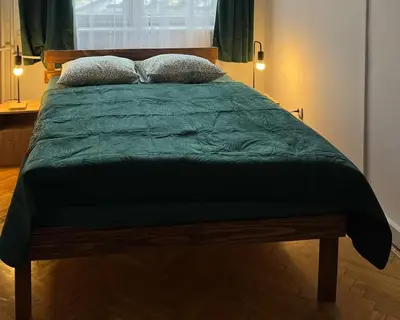 a bed with a green comforter and two pillows at TOM PRIVATE room in Kraków