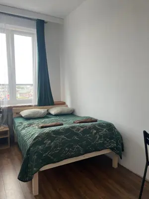 a bedroom with a bed with a green comforter and a window at TOM PRIVATE room in Kraków