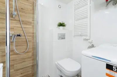 a white bathroom with a toilet and a shower at Świętego Filipa Apartments Cracow by Noclegi Renters in Kraków