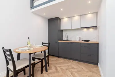 a kitchen with a wooden table and chairs and a counter at Świętego Filipa Apartments Cracow by Noclegi Renters in Kraków