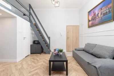 a living room with a couch and a staircase at Świętego Filipa Apartments Cracow by Noclegi Renters in Kraków