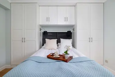 a bed with white cabinets and a tray with flowers on it at Air Conditioned Apartment in Cracow with Parking, Desk and Bathtub by Noclegi Renters in Kraków