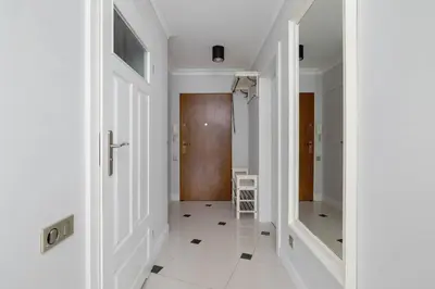 a hallway with white walls and white floors and a door at Air Conditioned Apartment in Cracow with Parking, Desk and Bathtub by Noclegi Renters in Kraków