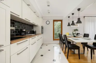 a kitchen with white cabinets and a table with chairs at Air Conditioned Apartment in Cracow with Parking, Desk and Bathtub by Noclegi Renters in Kraków