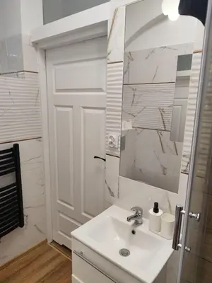 a white bathroom with a sink and a mirror at Capsule 12- Old Town , Steps to the Station , Maximum Convenience in Kraków