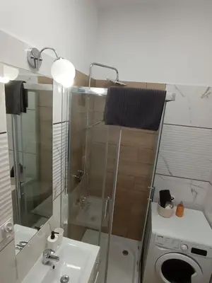 a bathroom with a sink and a washing machine at Capsule 12- Old Town , Steps to the Station , Maximum Convenience in Kraków