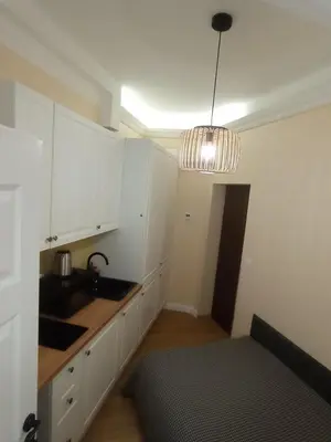 a kitchen with white cabinets and a pendant light at Capsule 12- Old Town , Steps to the Station , Maximum Convenience in Kraków
