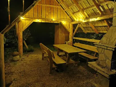 a wooden picnic table and chairs in a cabin at night at Hope Mountain Escape Poland, Charming Barrel House in Szczawa