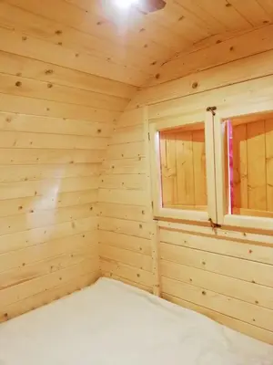 a wooden room with two windows in a log cabin at Hope Mountain Escape Poland, Charming Barrel House in Szczawa