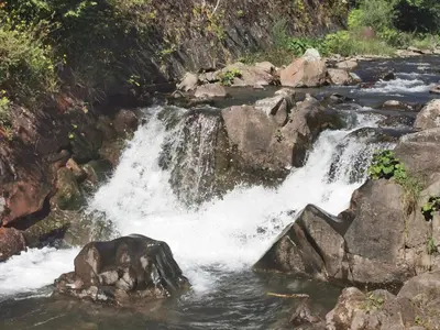 a waterfall in a river with rocks at Hope Mountain Escape Poland, Charming Barrel House in Szczawa