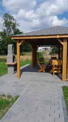a wooden pavilion with a table and a bench at Apartament pod Groniem in Zawoja