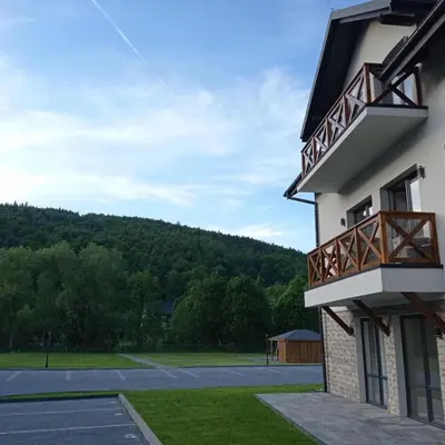 a building with a balcony and a parking lot at Apartament pod Groniem in Zawoja