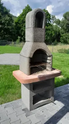 a stone pizza oven sitting on top of a field at Apartament pod Groniem in Zawoja