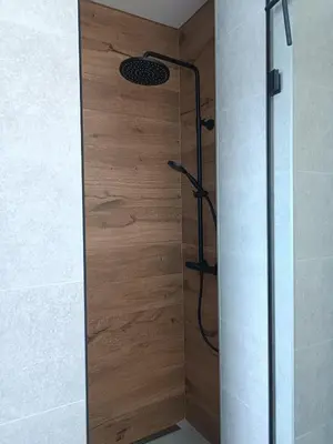 a shower in a bathroom with a wooden wall at Apartament pod Groniem in Zawoja