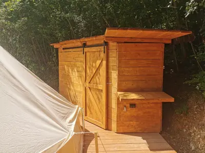 a wooden outhouse with a door on a wooden deck at Hope Mountain Escape Poland, Awesome Glamping Tent in Szczawa