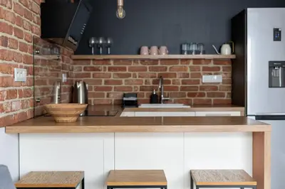 a kitchen with a counter and a brick wall at Cricoteque Residence - Luxury 1BR Riverside Suite in Kraków