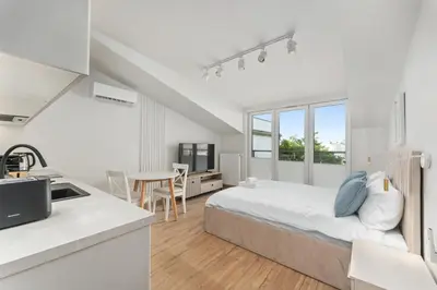 a white bedroom with a bed and a table at Kalwaryjska Elegant Stay Studios by BookingHost in Kraków