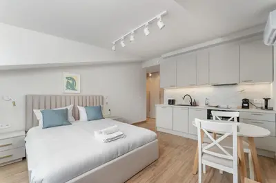 a white bedroom with a bed and a kitchen at Kalwaryjska Elegant Stay Studios by BookingHost in Kraków