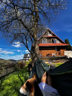a person lying in a hammock in front of a house at Dom Ponad Wsią in Zawoja