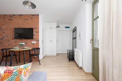 a living room with a table and a brick wall at Stylish Apartment Dietla with Balcony in Kraków by Noclegi Renters in Kraków