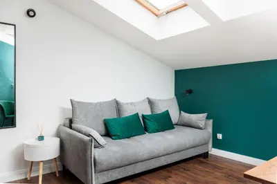 a couch with two green pillows in a living room at The Vitrail Apartments - by Upstairs in Kraków