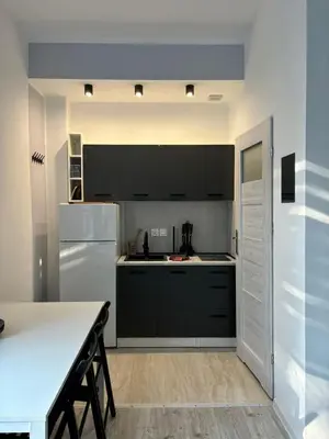 a kitchen with black cabinets and a white refrigerator at Apartament w Kocierzu in Kocierz Rychwałdzki