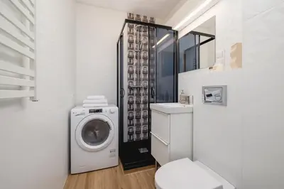 a white bathroom with a washing machine in it at Studio apartment - Kalwaryjska 34 street in Kraków
