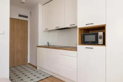 a kitchen with white cabinets and a microwave at Studio apartment - Kalwaryjska 34 street in Kraków