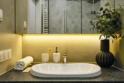 a bathroom sink with a vase and a plant at City Dreams Apartment in Kraków