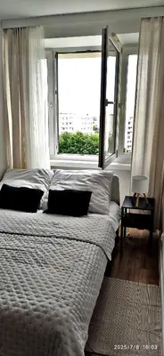 a bed in a bedroom with a large window at Przy Parku Wyspiańskiego in Kraków