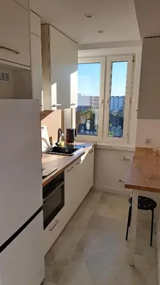 a kitchen with white cabinets and a table and windows at Przy Parku Wyspiańskiego in Kraków