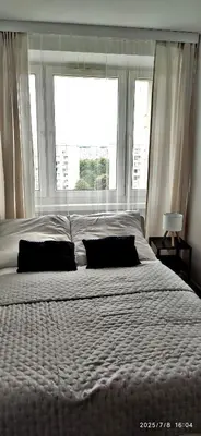 a large bed with two pillows in front of a window at Przy Parku Wyspiańskiego in Kraków