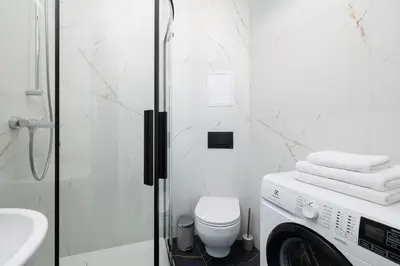 a white bathroom with a washing machine in it at Studio apartment - 65 Długa Street in Kraków