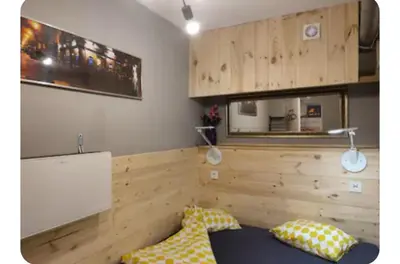 a bedroom with a wooden wall with two pillows at Pokój kapsułowy 7 in Kraków