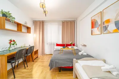 a white room with a bed and a table at Krakow Cozy Nest Free Parking - By Hosty in Kraków