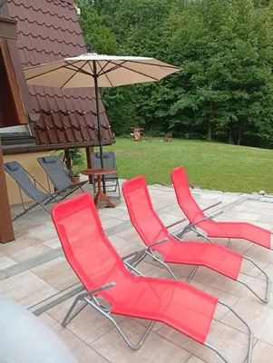 three red chairs and an umbrella on a patio at Szumią Dęby - Marcyporęba in Marcyporęba