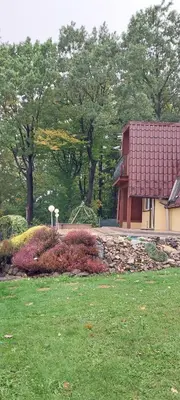 a building with a red roof in a park at Szumią Dęby - Marcyporęba in Marcyporęba