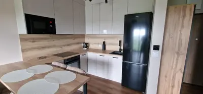 a kitchen with a black refrigerator and a table at Sunrise Apartament in Kraków