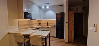 a kitchen with a table and a black refrigerator at Sunrise Apartament in Kraków