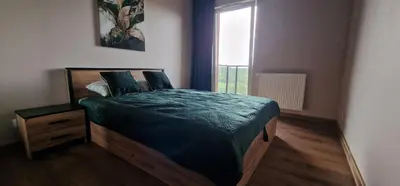 a bedroom with a bed with a green comforter and a window at Sunrise Apartament in Kraków