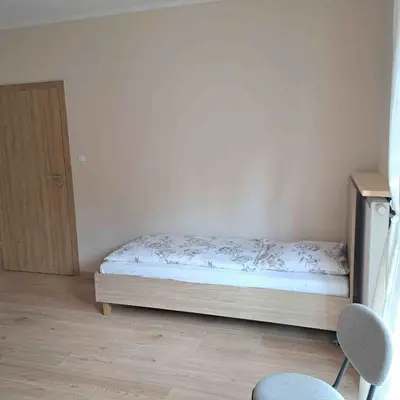 a small bedroom with a bed and a cabinet at Niwy8Rooms in Oświęcim