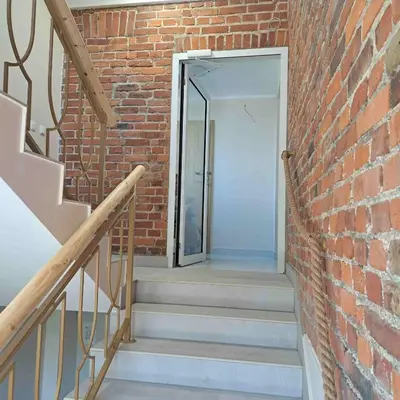 a brick wall with a door and stairs next to it at Niwy8Rooms in Oświęcim
