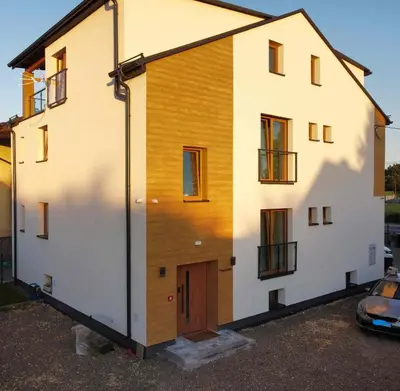 a house with a wooden facade and a garage at Niwy8Rooms in Oświęcim