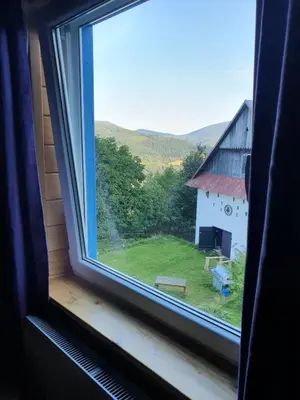 a window with a view of a field and a barn at Agroturystyka Z Głową w Chmurach - Zawoja in Zawoja