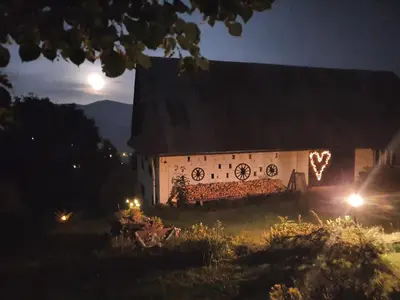 a building with christmas lights on the side of it at night at Agroturystyka Z Głową w Chmurach - Zawoja in Zawoja