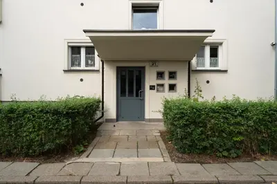 a white house with a blue door and bushes at Grzegórzki Comfort Apartment by BookingHost in Kraków