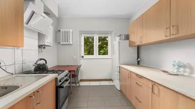 a kitchen with wooden cabinets and a white refrigerator at Grzegórzki Comfort Apartment by BookingHost in Kraków