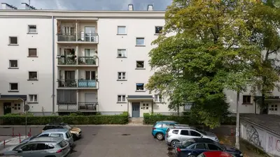 a large white building with cars parked in a parking lot at Grzegórzki Comfort Apartment by BookingHost in Kraków