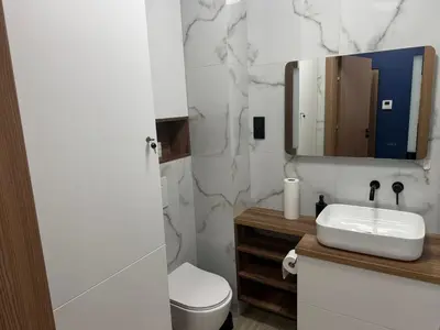 a bathroom with a sink and a toilet and a mirror at Apartament Pod Areną in Kraków