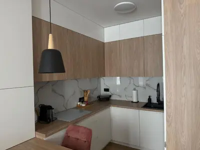 a kitchen with white cabinets and a black lamp at Apartament Pod Areną in Kraków